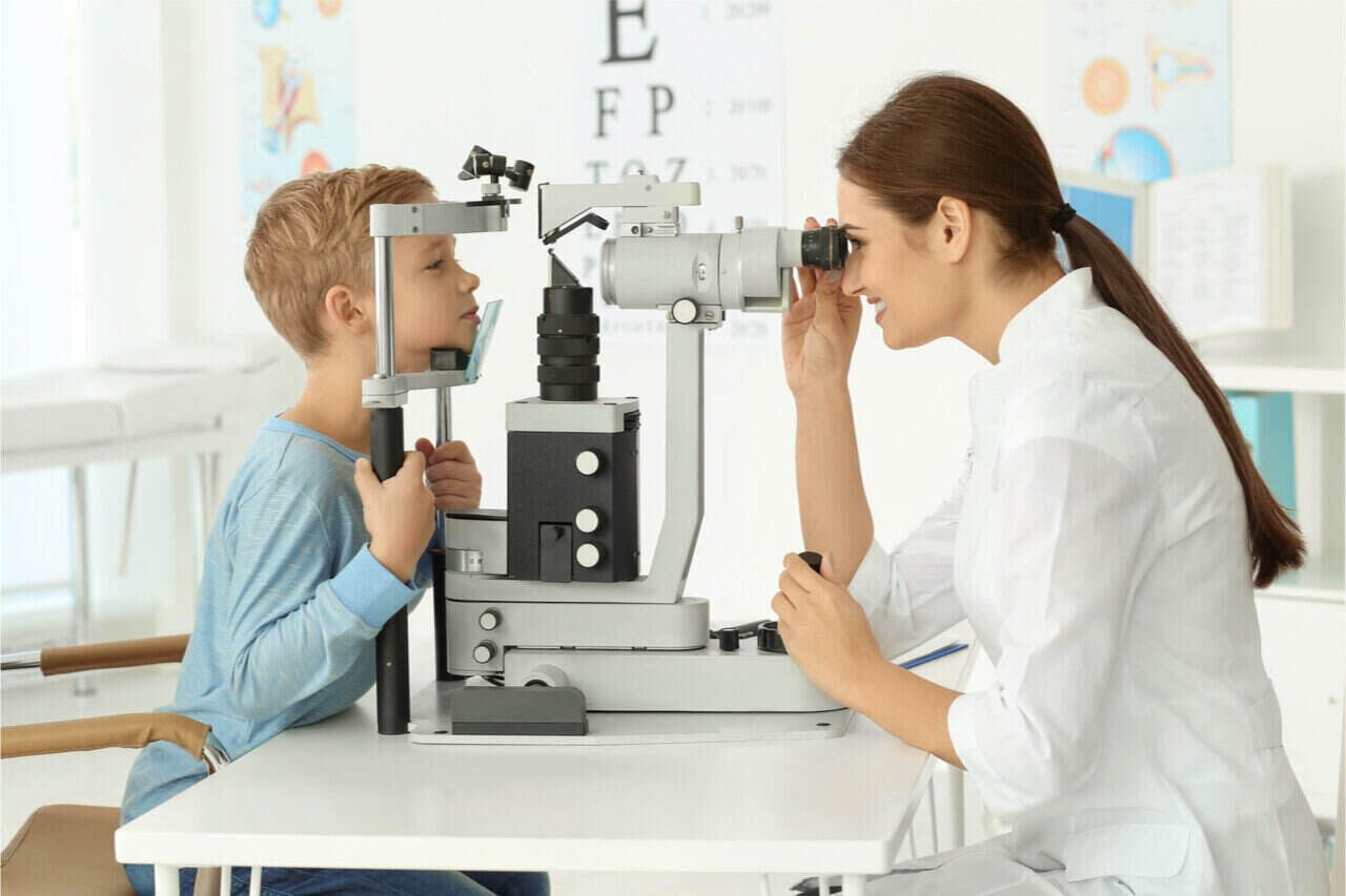 A female ophthalmologist applying eye health services to a young boy.