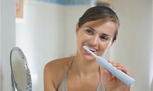 The woman loves to use an electric toothbrush to clean her teeth.